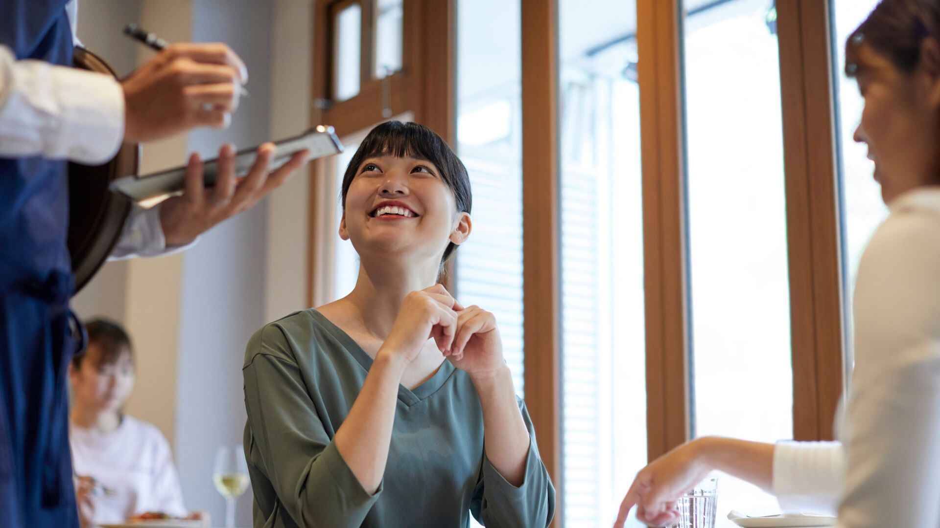 Smiling woman in a restaurant interacting with a server while placing an order, representing positive customer experience