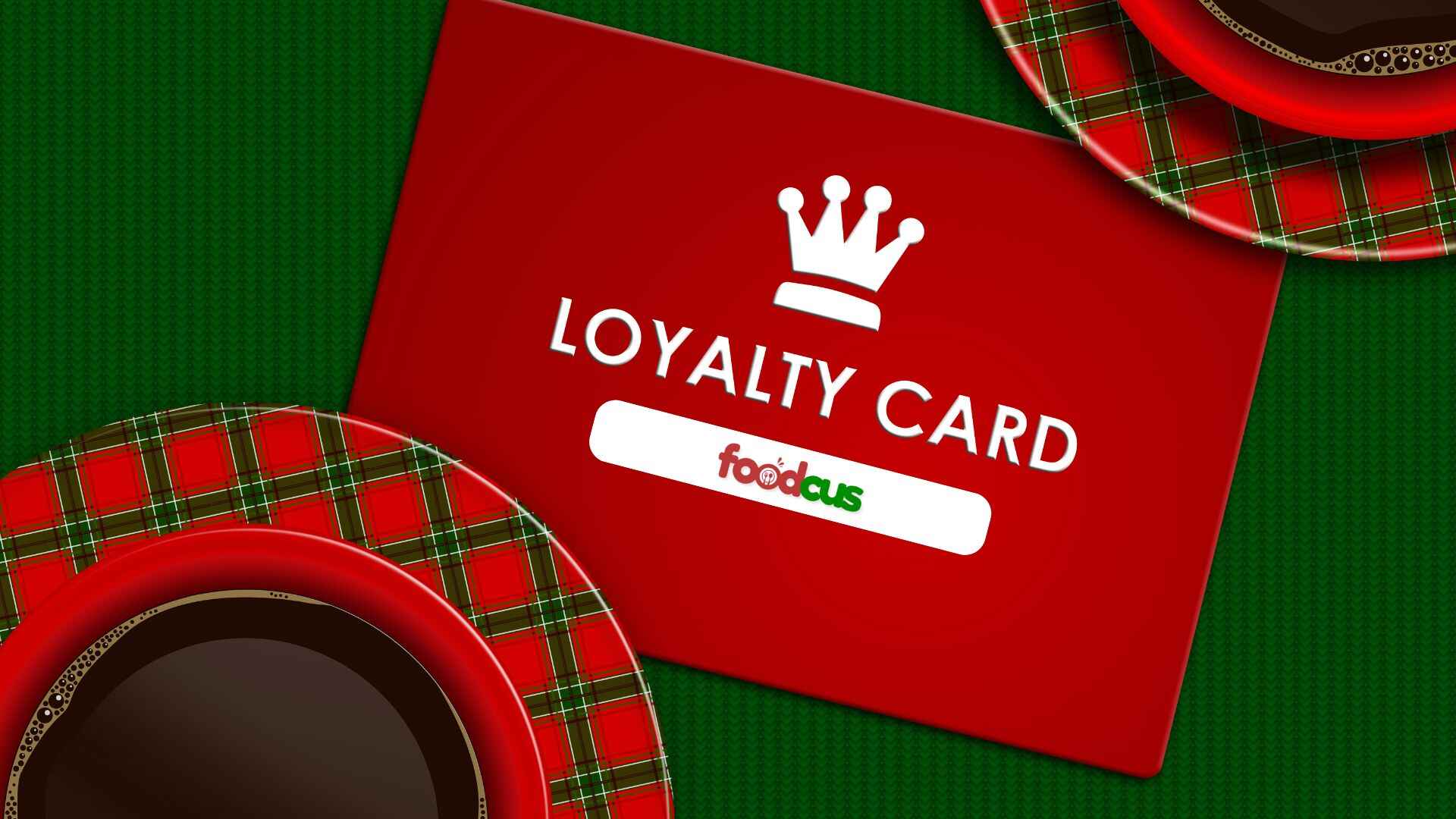 Red loyalty card with a crown icon and Foodcus logo placed beside festive coffee cups and saucers, symbolizing customer rewards and retention.
