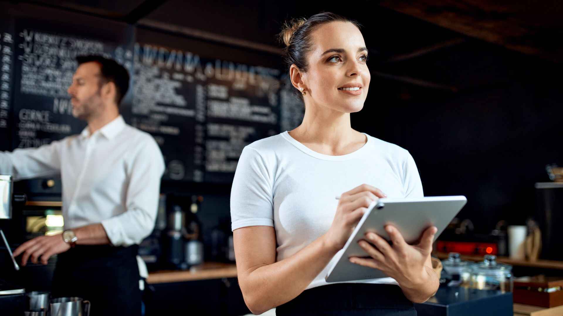Smiling restaurant staff member using a digital tablet, representing the adoption of digital loyalty solutions in modern restaurant operations.