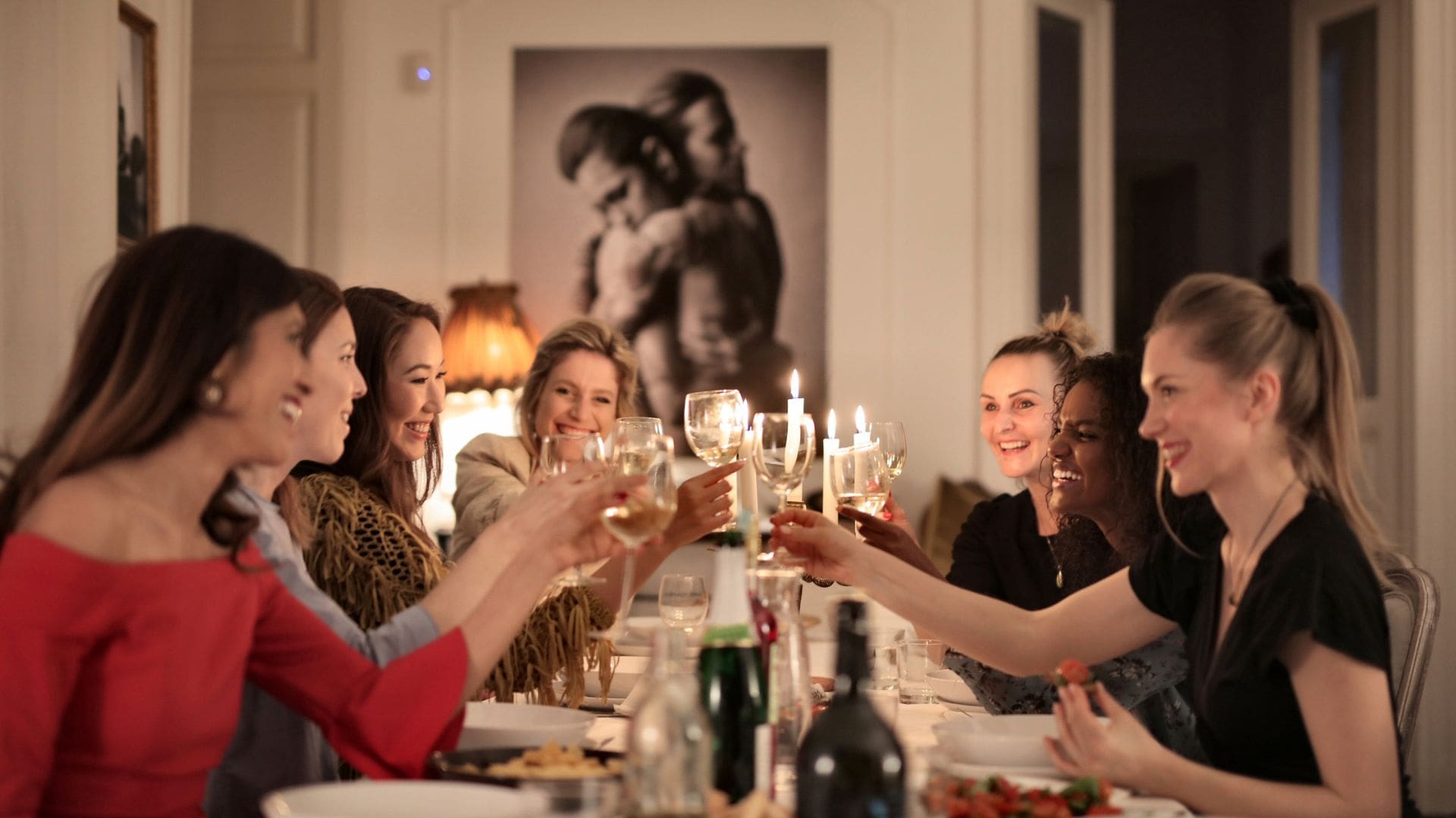 Group of women toasting with wine glasses around a beautifully set dinner table during a special occasion celebration