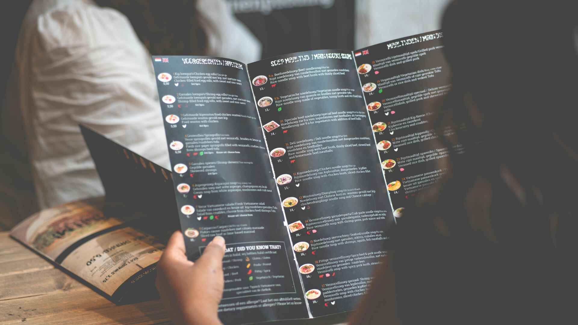 Close-up of a person analyzing a restaurant menu with detailed listings and prices to assess popular and less popular dishes